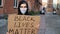 Man in mask stands with cardboard poster in hands - BLACK LIVES MATTER