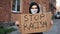 Man in mask stands with cardboard poster in hands - STOP RACISM