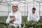 Man with mature woman standing in greenhouse