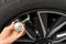 Man measuring car tire pressure with air gauge, closeup.