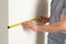 Man measuring white wall indoors. Construction tool