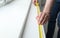 Man measuring white windowsill indoors, closeup view. Construction tool