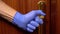 man in medical gloves opens the door, holding on to the handle
