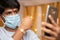 Man in medical mask busy on mobile phone and showing Rakhi or RakshaBandhan to sister or family friends at festival ceremony