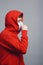 Man in medical mask coughing on gray studio background, concept of prevention viral deseases, person in red sweatshirt with