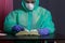 A man in a medical mask, glasses, rubber gloves and a raincoat. Front open book. Leisure during an epidemic