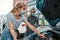 Man in medical mask helping girl with her auto while she is examining, looking at her broken car with open hood