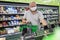 A man in a medical mask picks vegetables in a supermarket. Big choice. Healthy eating and vegetarianism. Coronavirus pandemic