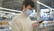 Man in a medical mask and rubber gloves stands in a supermarket with a smartphone. Protective measures against covid-19.