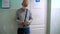 A man in a medical mask stands in a queue in the corridor of the hospital under the door of the office and waits for a doctor`s ap