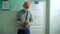 A man in a medical mask stands in a queue in the corridor of the hospital under the door of the office and waits for a doctor`s ap