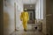 A man - a medical worker or a doctor in a yellow suit of bacterial and chemical protection is walking along the corridor of an old
