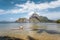 Man meditating on bamboo float in shallow lagoon water and Islands of Cadlao bay in a distance. Palawan, Philippines