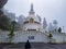 Man meditating at buddhist shanti stupa covered with misty fog at morning from different angle