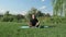 Man meditating outdoors with online guiding on laptop. Male practicing yoga in park with river on background. Young man sitting in