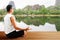 Man meditating on wooden floor on blurred lake background