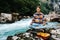 Man in a meditative position with guitar sitting on the bank of a mountain river on a background of rocks and forest. Concept of