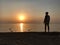 A man meets the dawn on the seashore. A man watches the morning sun over the ocean. Sunset on the coast, a sunny circle over the