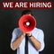 Man with megaphone and phrase WE ARE HIRING on background. Career promotion