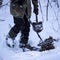 Man with a metal detector and a sapper shovel is looking for something in the winter forest