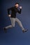 Man in mid-air. Full length of playful young man gesturing and smiling while jumping against Pacific Blue background