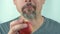 A man of middle ages with beard and mustache eating a red apple, close-up, 4K