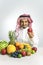 Man from the Middle East in a traditional Arab national costume, stands in front of a mountain of fresh fruit, smiles joyfully and