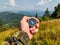 Man in military clothes holding a compass in a hand on the carpathian mountains background