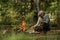 Man in military clothes is making campfire in the woods.