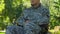 Man in military uniform sitting in wheelchair, resting enjoying nature in park