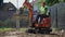 A man on a mini-excavator levels a piece of land, loosens the soil.