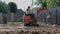 A man on a mini-excavator levels a piece of land, loosens the soil.