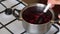 A man mixes a spoonful of frozen cranberries in a saucepan. Prepares mashed potatoes for marshmallow.