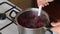 A man mixes a spoonful of frozen cranberries in a saucepan. Prepares mashed potatoes for marshmallow.
