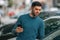 Man with mobile phone at dealership looking at cars