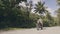 Man motorcyclist driving on motorbike on road with green palm trees landscape. Mature man riding motorcycle on road in