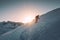 Man mountaineer with trekking pole climbing on snowy hill and sunshine at Ryten mount