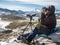 Man in the mountains looking through binoculars under blue sky