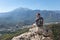 The man on a mountaintop admiring the surrounding mountain landscape