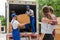 Man movers worker in blue uniform unloading cardboard boxes from truck.Professional delivery and moving service