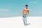 Man with muscular torso in jeans on sandy beach