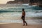 A man with a naked torso on the seashore. A lonely man stands on the beach. A man meets the sunset on the beach in Indonesia.