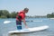 Man next to stand-up paddle board on lake