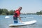 Man next to stand-up paddle board on lake