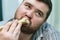 A man nibbles meat from a bone, close-up. A Hungry Fat Man. Portrait of a man eating pork. a manly man with a large bone, demonstr