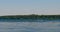 A man with oars sails in a canoe kayak boat on a river on a bright summer day against the backdrop of rocks and an island