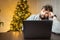 A man in the office, tired from work and shaggy, sits in front of a laptop and works