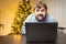 A man in the office, tired from work and shaggy, sits in front of a laptop and works