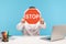 Man office worker in white shirt hiding face behind red stop traffic sign, sitting at workplace with laptop, symbol of prohibition