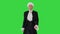 Man in old-fashioned laced frock coat and white wig walking in a mannered way looking at camera on a Green Screen